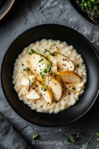 Risotto cremoso con taleggio e pere servito in piatto nero moderno – ricetta riso taleggio e pere
