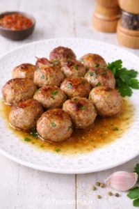 Polpette di carne fatte in casa, dorate e morbide, servite con il loro fondo di cottura