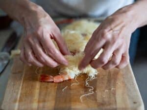 Gambero avvolto con pochi fili di pasta kataifi sul piano di lavoro